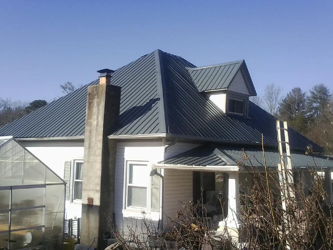 Dark blue standing seam metal roof on a white farmhouse with dormer — Slate & Tile Roof Repair by Roofing Brothers in Indiahoma
