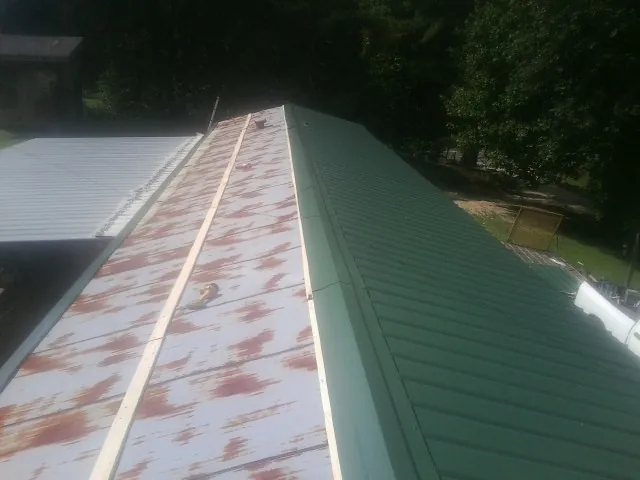 Old rusted panels beside newly installed green metal roofing — Wind Damage Roof Repair by Roofing Brothers in Indiahoma