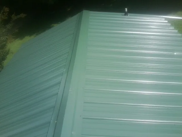 New green metal panels meeting at the ridge of a roof — Flat Roof Repair work by our crew in Indiahoma
