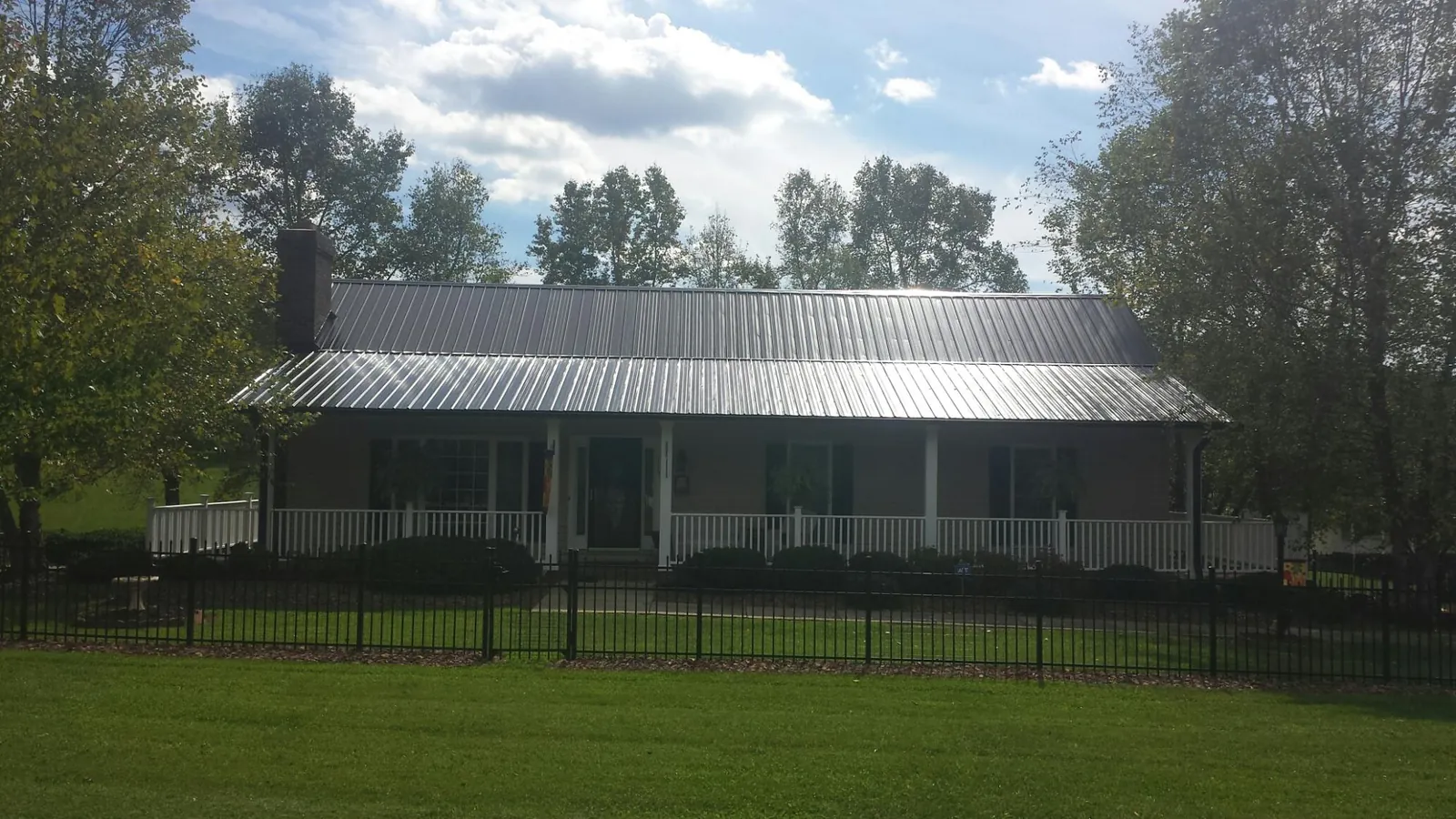 Gray metal roof on a brick ranch with a full width front porch — Gutter Guard Installation work by our crew in Indiahoma