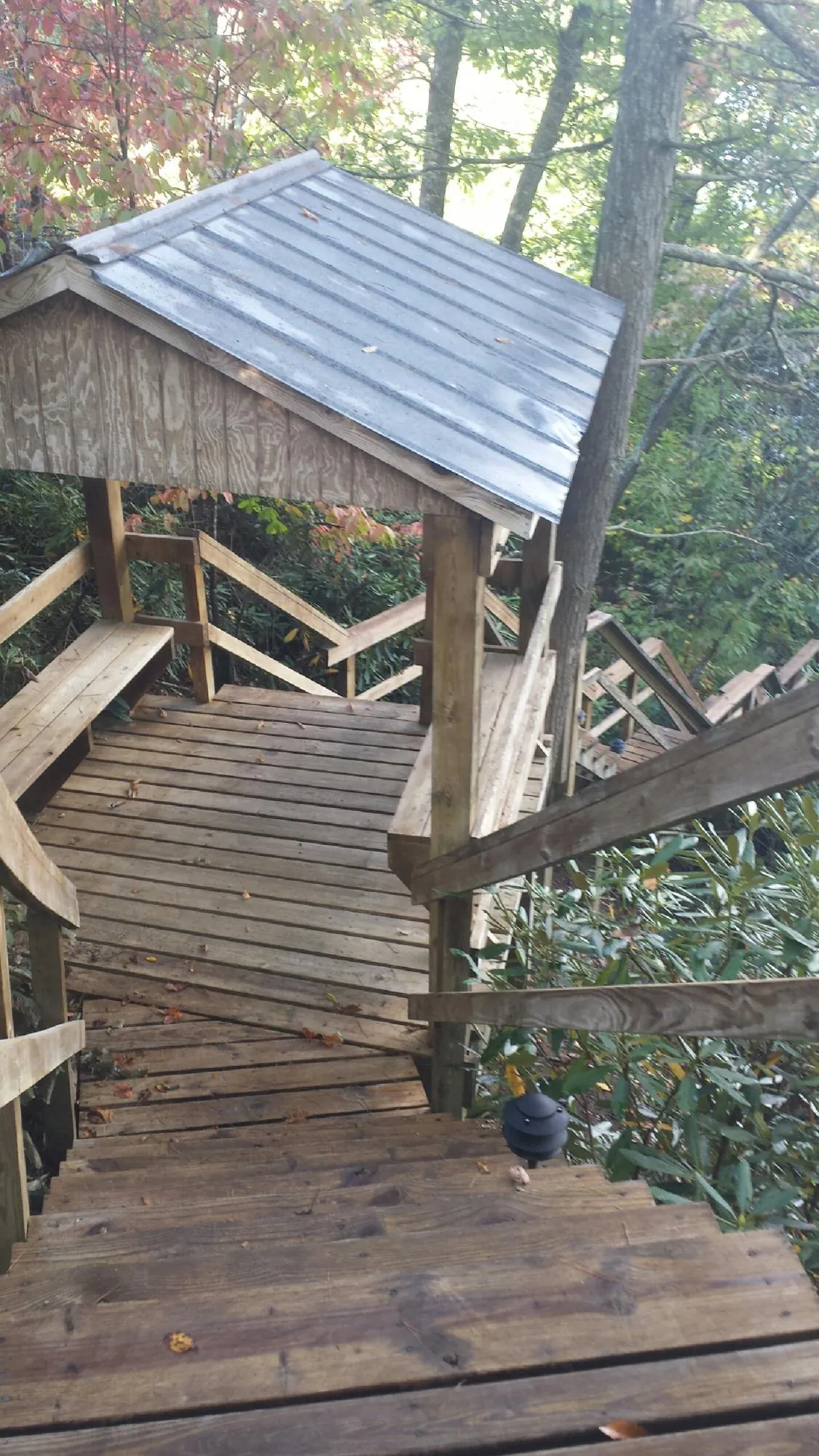 Metal roofed shelter over wooden steps on a wooded walkway in Indiahoma