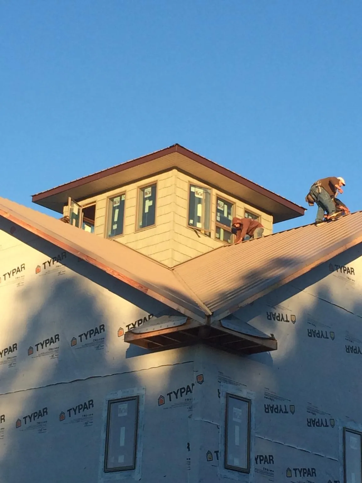 Roofers working around a rooftop cupola on a new metal roof at sunset — Roof Waterproofing in Indiahoma by Roofing Brothers